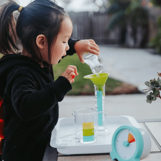 Child pouring water in the Liquid Lab from The Investigator Play Kit